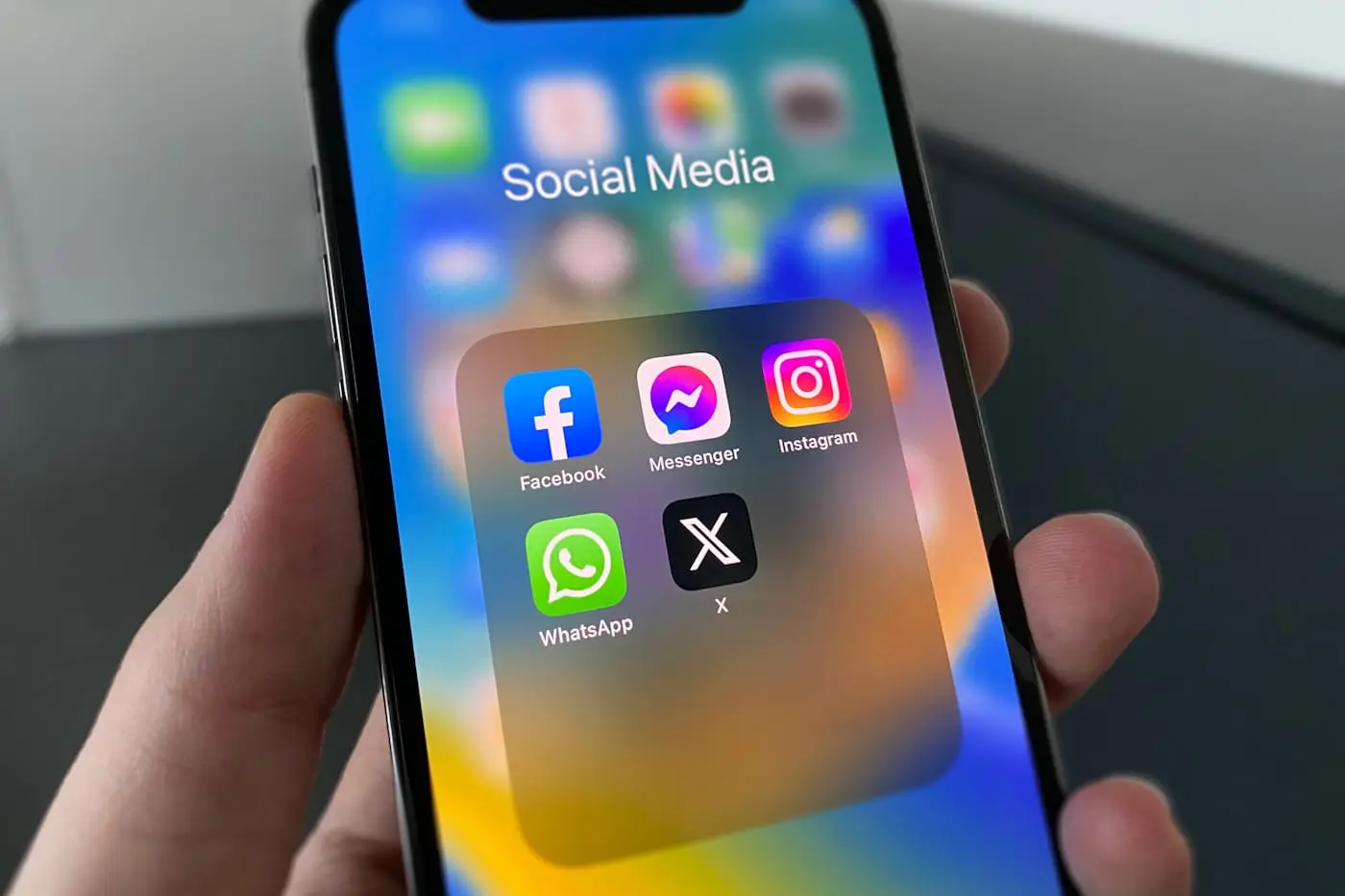 Mano sosteniendo un móvil con una carpeta de aplicaciones de redes sociales abierta